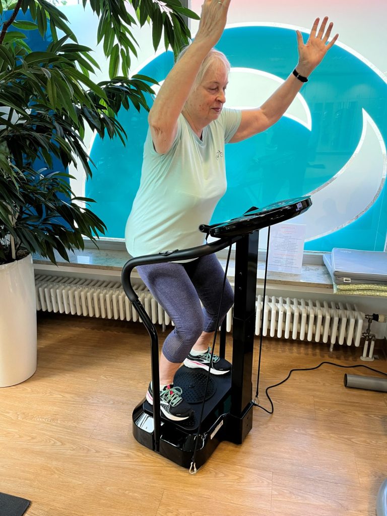 Leichte Kniebeuge mit erhobenen Armen auf der Vibrationsplatte – Vibrationstraining für Frauen bei FEMISPORT