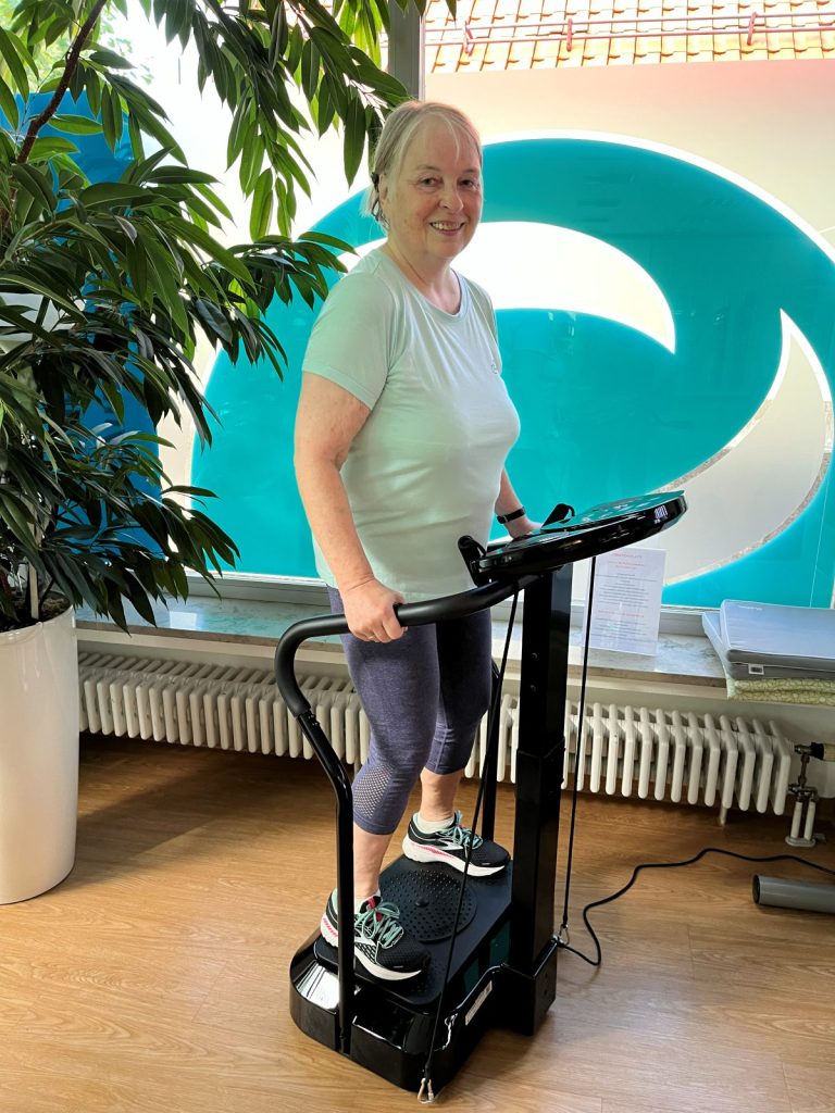 Frau beim Vibrationstraining: lächelnd auf der Vibrationsplatte im FEMISPORT Frauenfitnessstudio in Neusäß